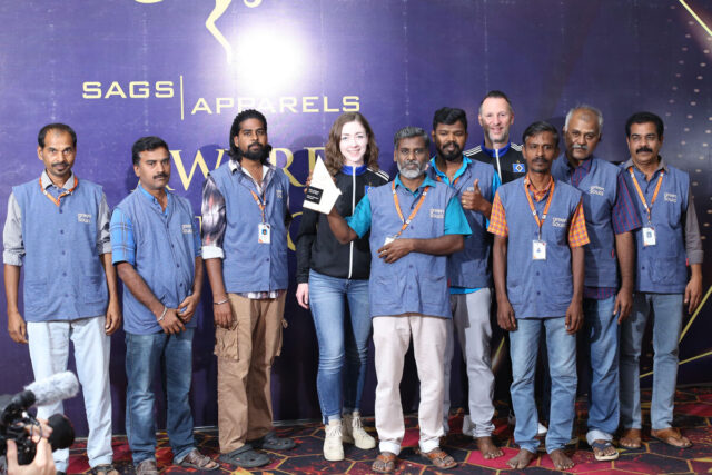 Das Bild zeigt zehn Personen vor einer Fotowand. Acht von ihnen tragen blaue Westen mit der Aufschrift „green souls“. Die beiden anderen tragen schwarze HSV-Trainingsjacken. Einer der Männer hält eine Auszeichnung in Form eines kleinen Pokals hoch.