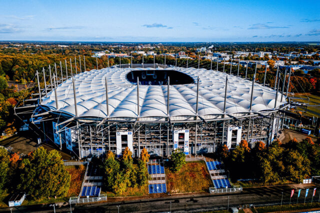 Das Foto zeigt eine Luftaufnahme des Volksparkstadions im Herbst. Die Perspektive ist in Richtung Norden ausgerichtet. Die Bäume im Volkspark und um das Stadion herum haben zum Teil rote und orangefarbene Blätter.