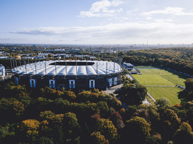Das Titelfoto zeigt das Volksparkstadion, die Alexander-Otto-Akademie und die Trainingsplätze aus der Luftperspektive. Im Hintergrund sind Gebäude der Hamburger Innenstadt zu erkennen.