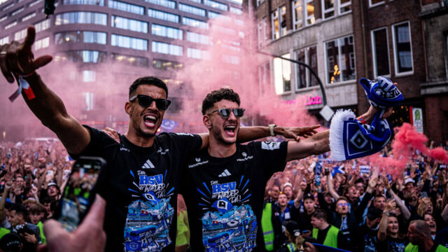Das Titelfoto zeigt Robert Glatzel und Daniel Elfadli beim Feiern. Beide tragen das Aufstiegsshirt, eine Sonnenbrille und stehen Arm in Arm nebeneinander. Den anderen Arm strecken sie in die Luft. Im Hintergrund sind eine Menschenmenge und roter Rauch zu erkennen.